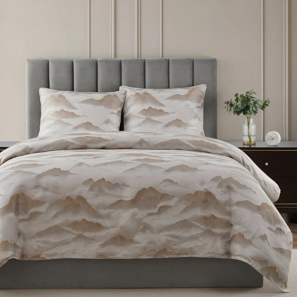 Bed with mountain-patterned bedding in a bedroom setting