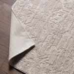 Textured beige rug on a wooden floor