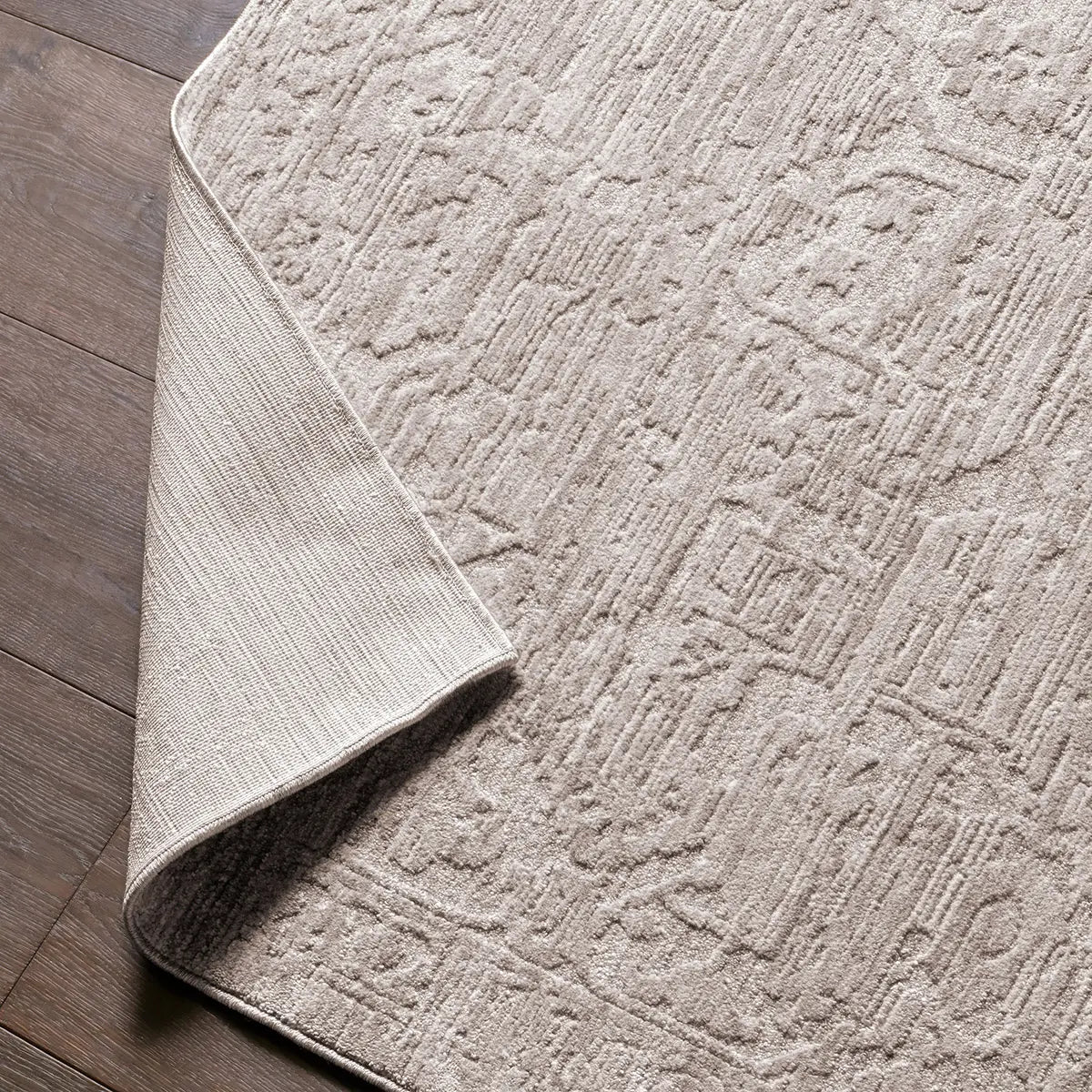 Textured beige rug on a wooden floor