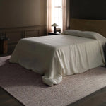 Bed with a beige blanket in a dimly lit bedroom