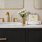 Bathroom vanity with gold fixtures, black cabinets, and decorative items.