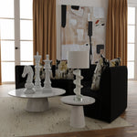 Modern living room with black sofa, white coffee table, and decorative items.