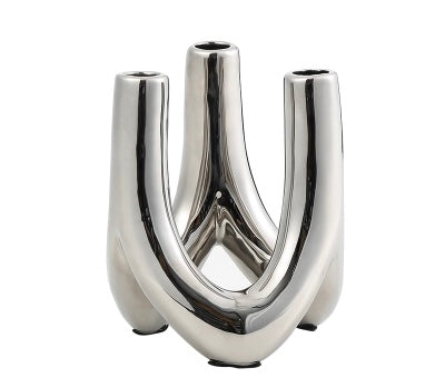A silver metal candle holder with a geometric design, featuring a reflective surface and a cylindrical shape with two protruding arms.