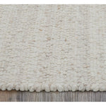 Close-up of a textured beige rug on a wooden floor