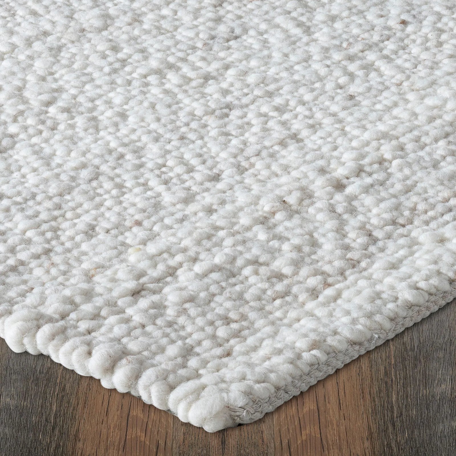 Close-up of a textured white rug on a wooden floor