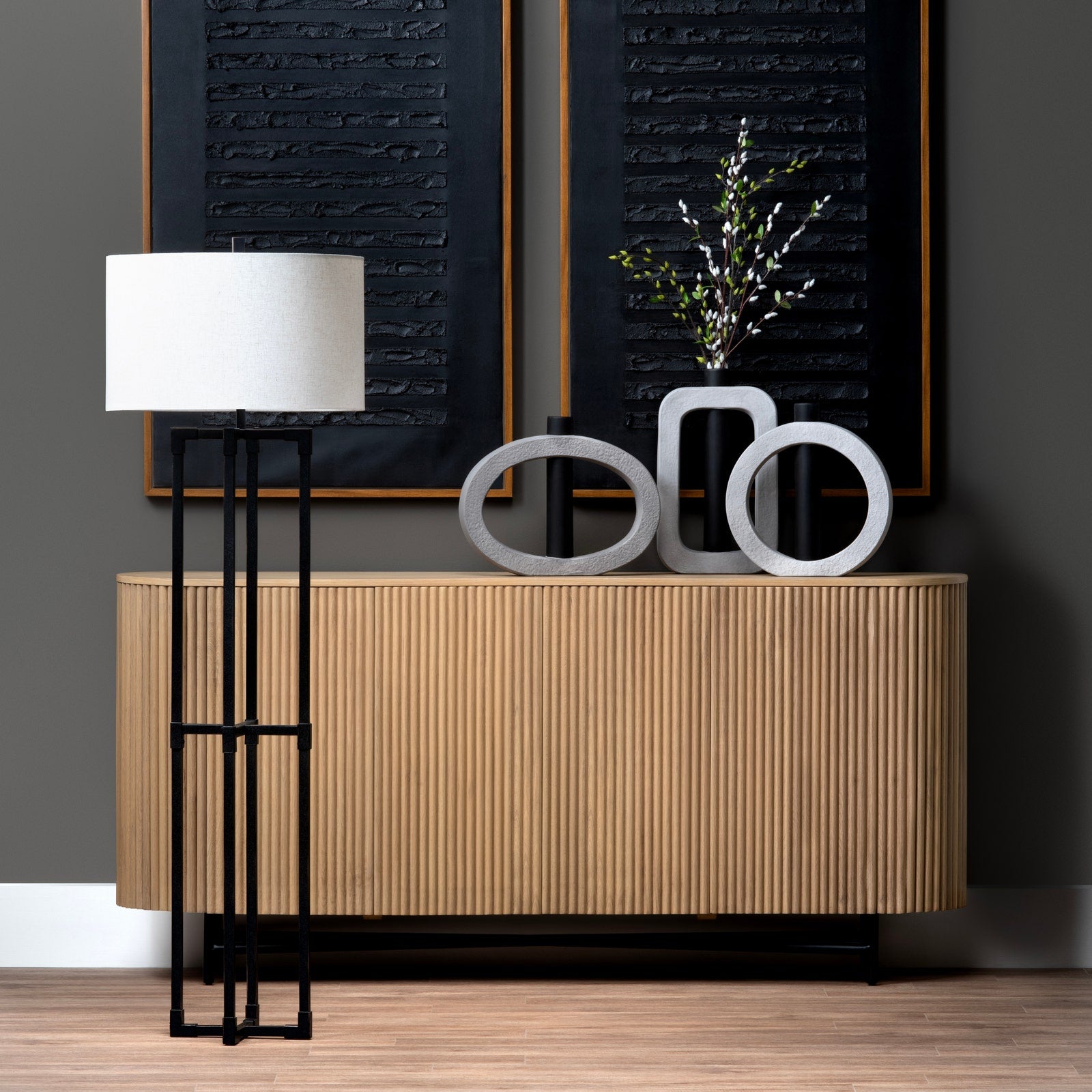 Modern interior with wooden sideboard, black floor lamp, and decorative items against a dark wall.