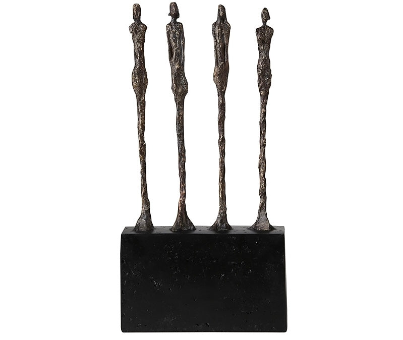 A sculpture of three figures standing in a line on a black base, likely made of bronze or a similar metallic material.