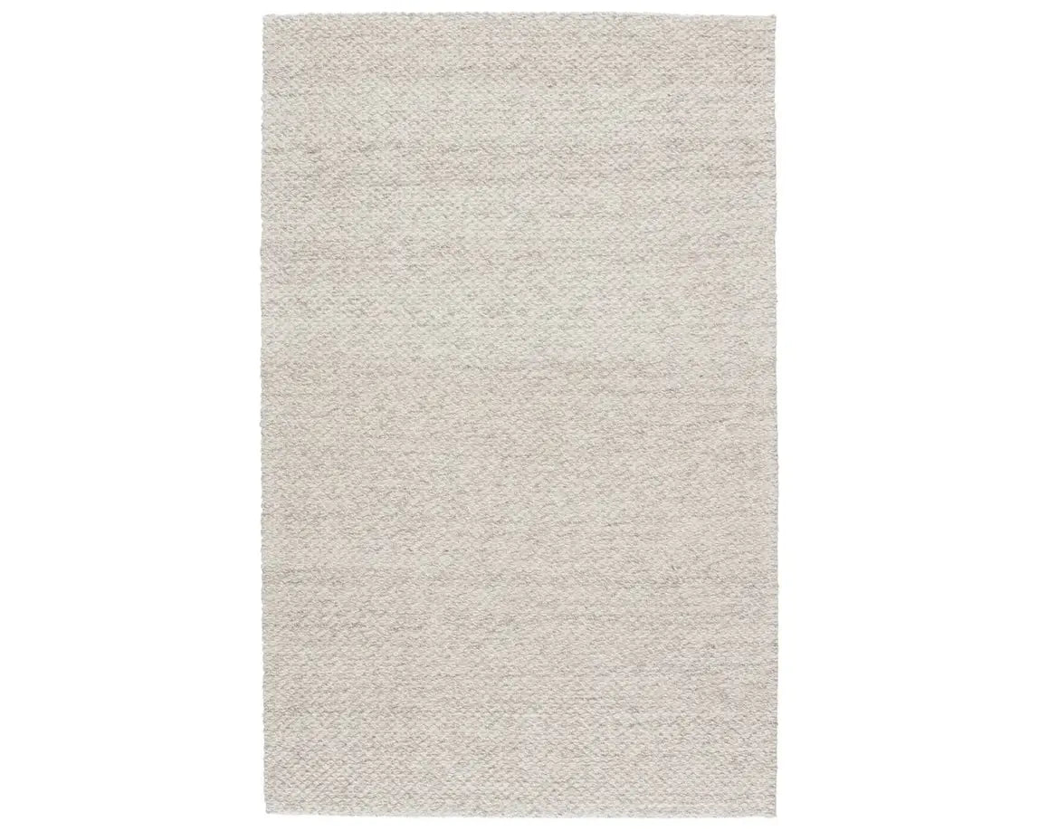 A beige, solid color wool area rug handwoven with a visible texture.