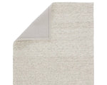 A beige, solid color wool area rug handwoven with a visible texture.