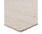 A beige, solid color wool area rug handwoven with a visible texture.