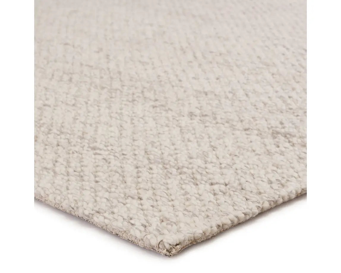 A beige, solid color wool area rug handwoven with a visible texture.