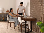 Man and woman sitting at a dining table with a geometric wall design in the background