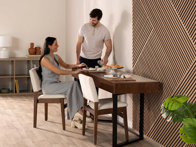 Man and woman sitting at a dining table with a geometric wall design in the background