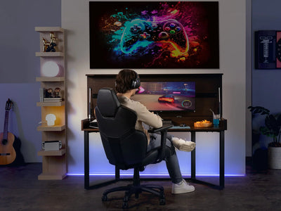 Person playing video games in a home setup with a large screen displaying colorful graphics.