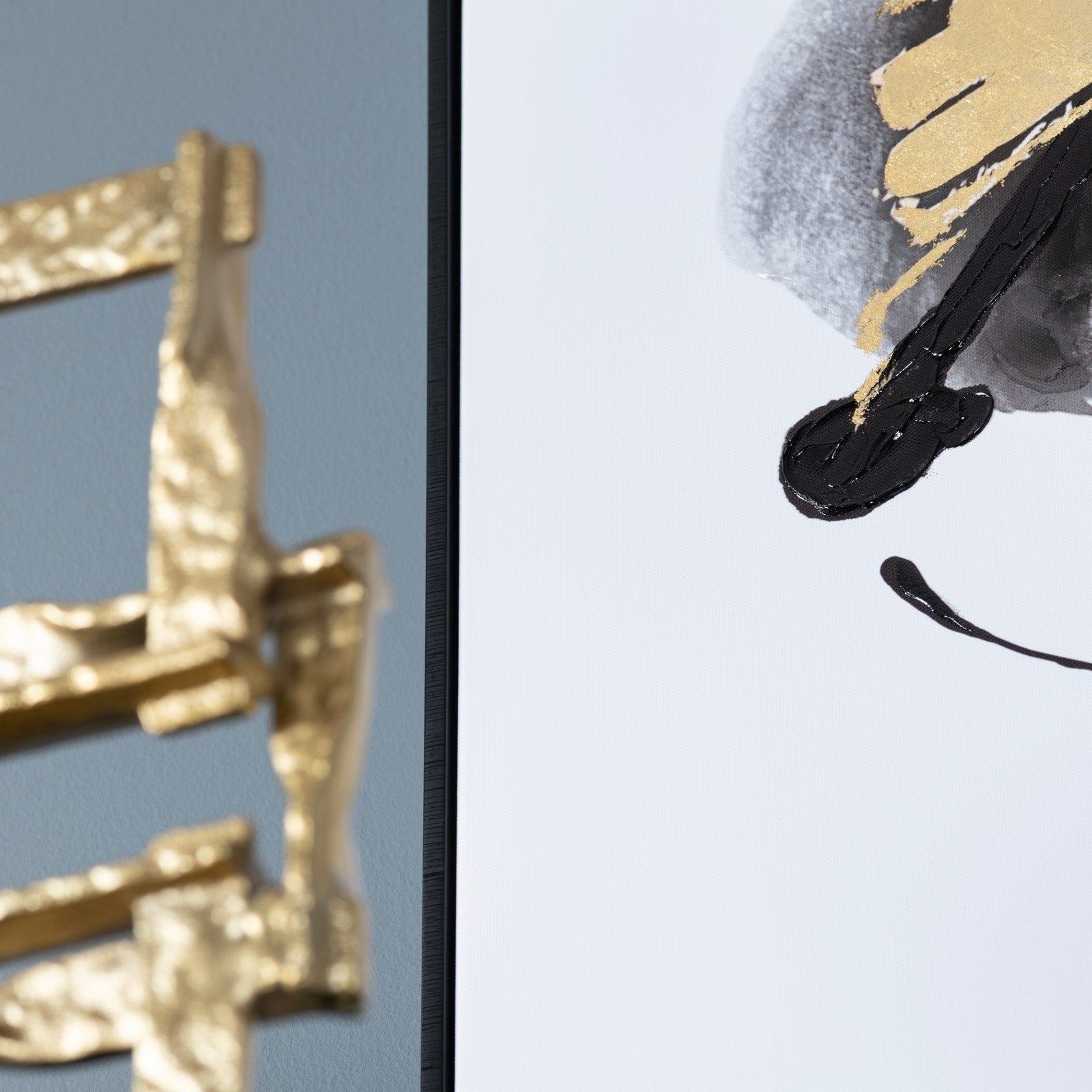 Two canvas paintings with abstract black and gold designs, set side by side.