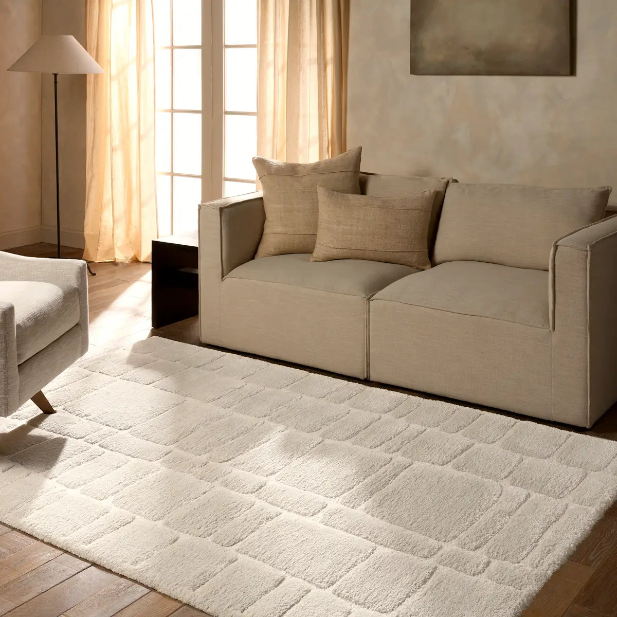 Living room with beige sofa, armchair, and textured rug.