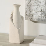 Textured vase on a wooden surface with abstract art in the background