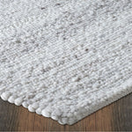 Close-up of a textured gray rug on a wooden floor