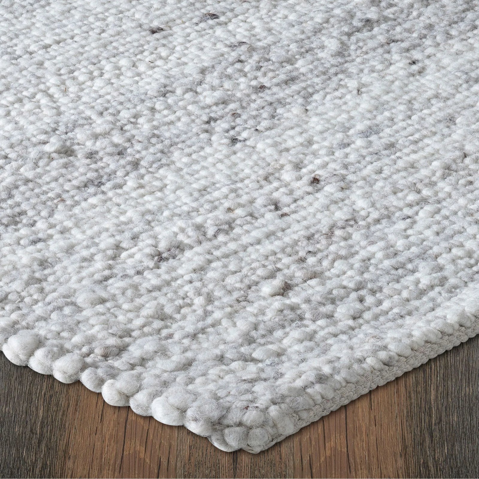 Close-up of a textured gray rug on a wooden floor