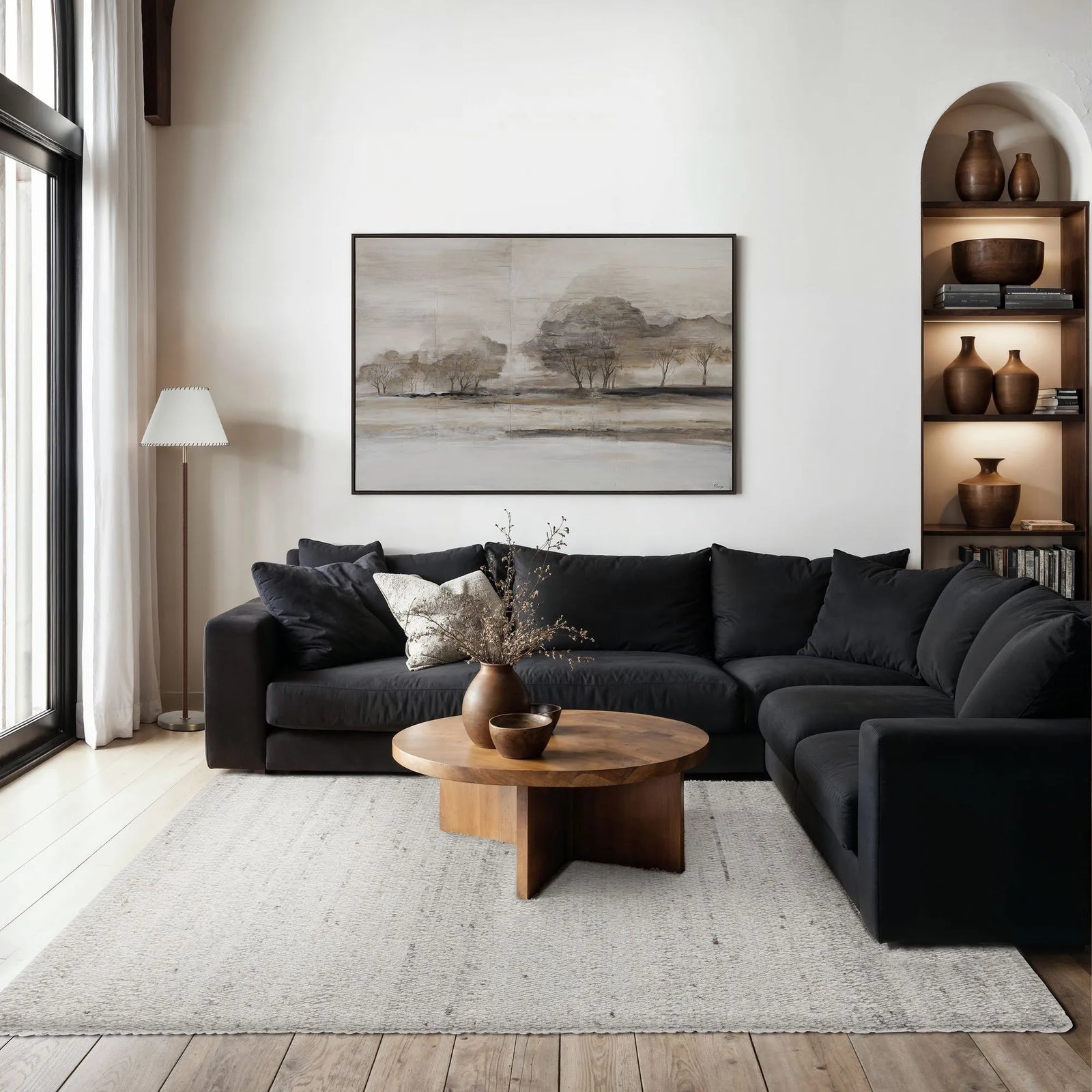 Modern living room with black sectional sofa, wooden coffee table, and abstract painting on wall.