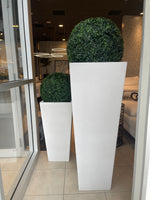 Two white, rectangular, textured planters placed side by side with green plants inside, likely used for decorative purposes in a home or office setting.