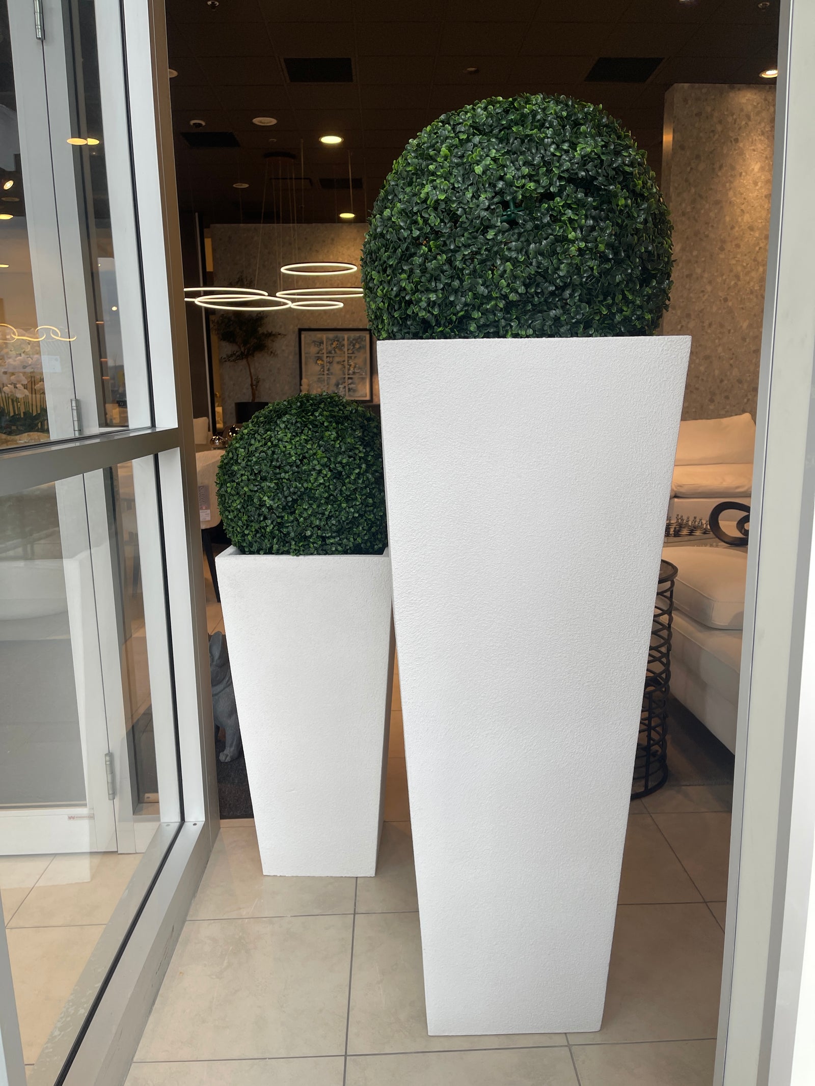Two white, rectangular, textured planters placed side by side with green plants inside, likely used for decorative purposes in a home or office setting.