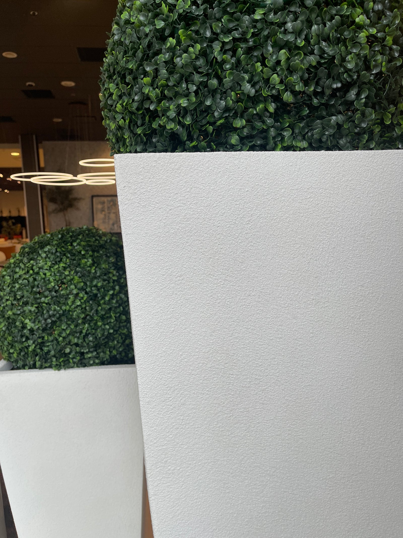 Two white, rectangular, textured planters placed side by side with green plants inside, likely used for decorative purposes in a home or office setting.