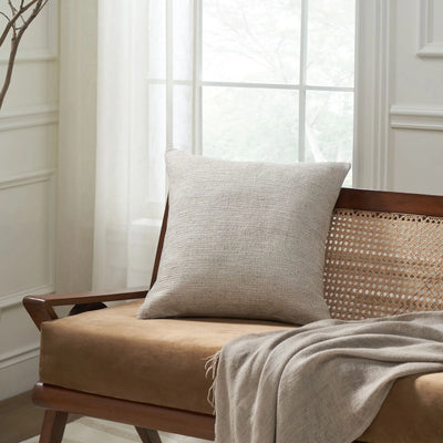 Beige pillow on a wooden chair with a light background