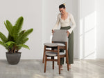 Woman arranging chairs in a room with a potted plant
