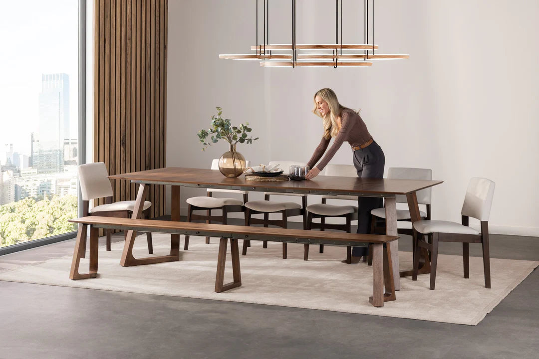 Dining room with a wooden table and chairs, a woman arranging items on the table.