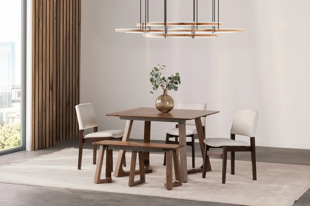 Dining room with wooden table, chairs, and bench on a light gray rug.
