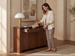Woman organizing a wooden sideboard in a home setting