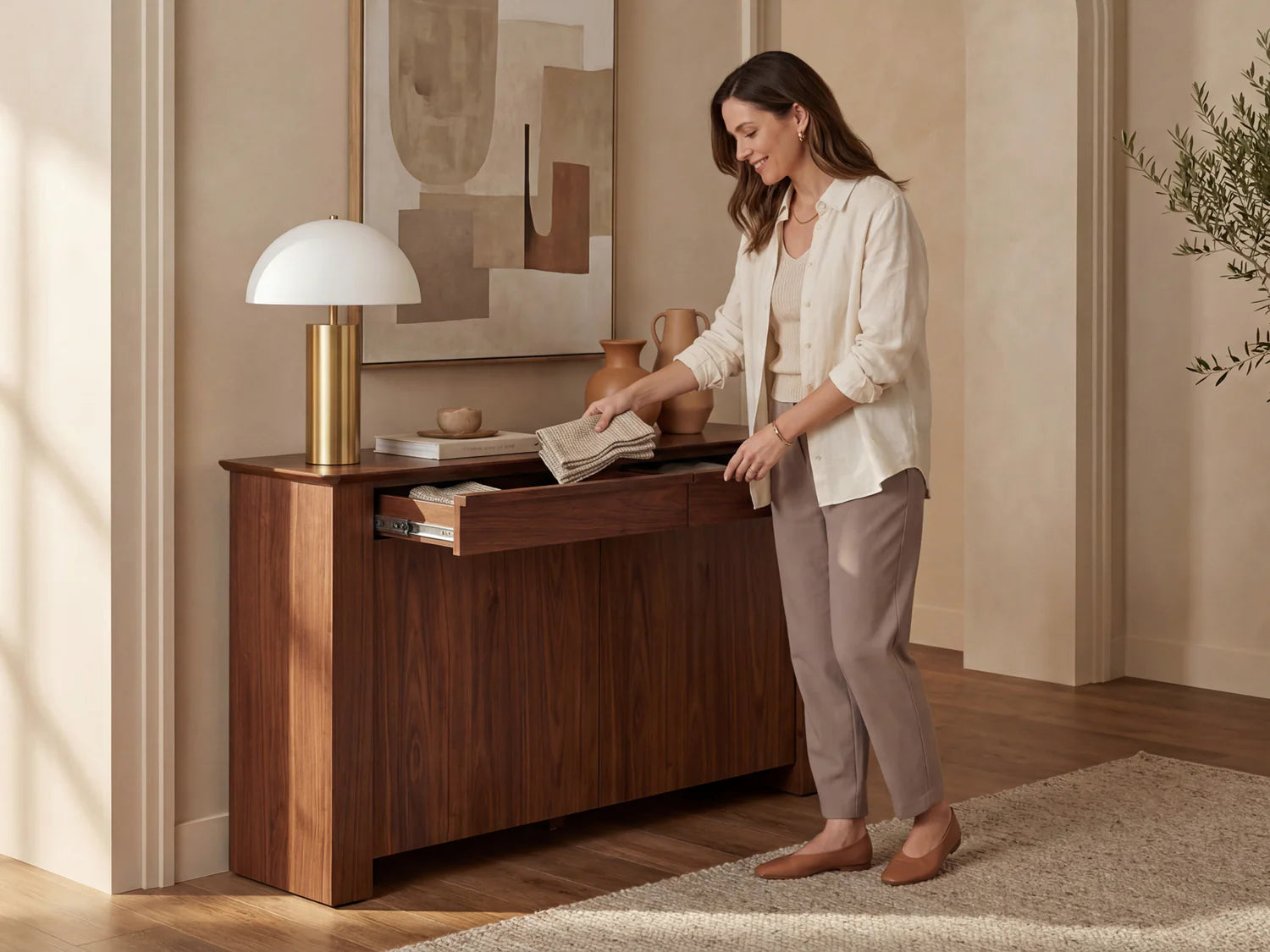 Woman organizing a wooden sideboard in a home setting