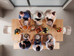 Top-down view of a family gathered around a dining table with food.