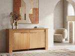 Wooden sideboard in a modern living room with abstract art and a chair.