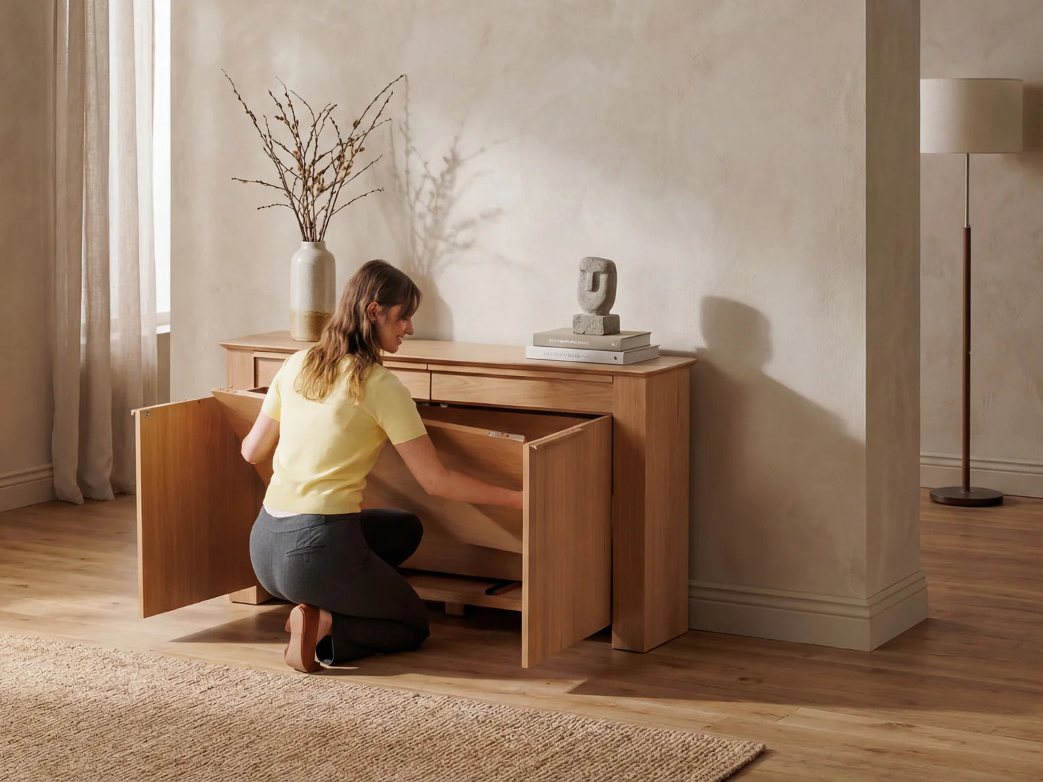 Woman assembling a wooden sideboard in a room with a lamp and vase.
