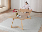 Woman arranging a wooden table in a minimalistic room with a rug and vase.