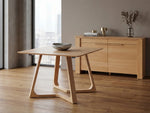Wooden table with a bowl on a wooden floor in a room with a large window.