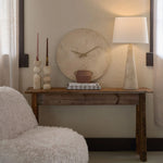 Wooden console table with decorative items against a wall with a clock.