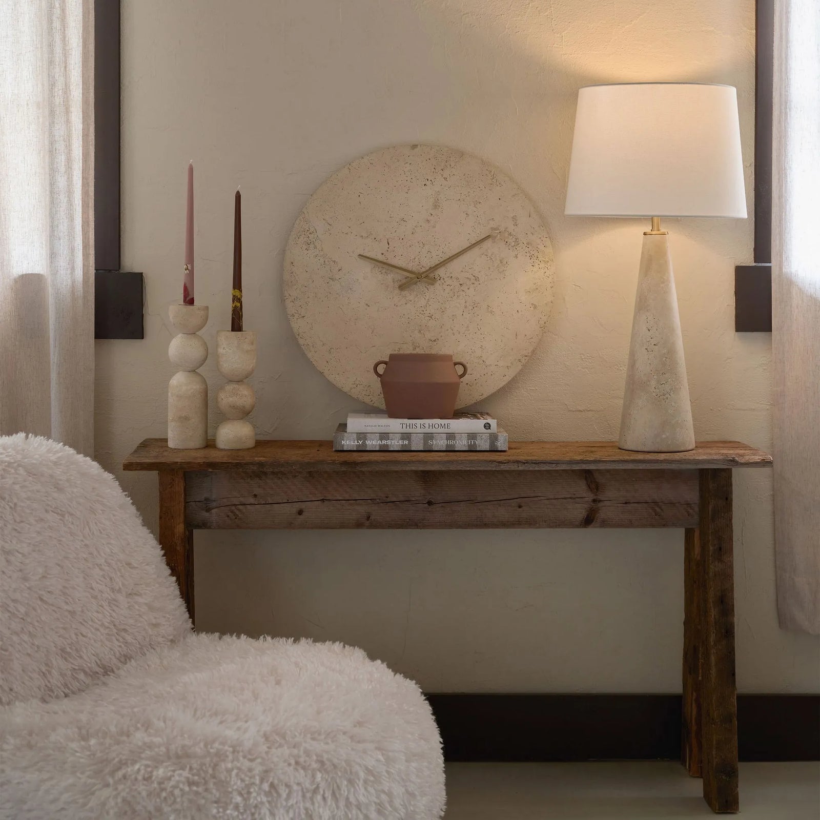 Wooden console table with decorative items against a wall with a clock.