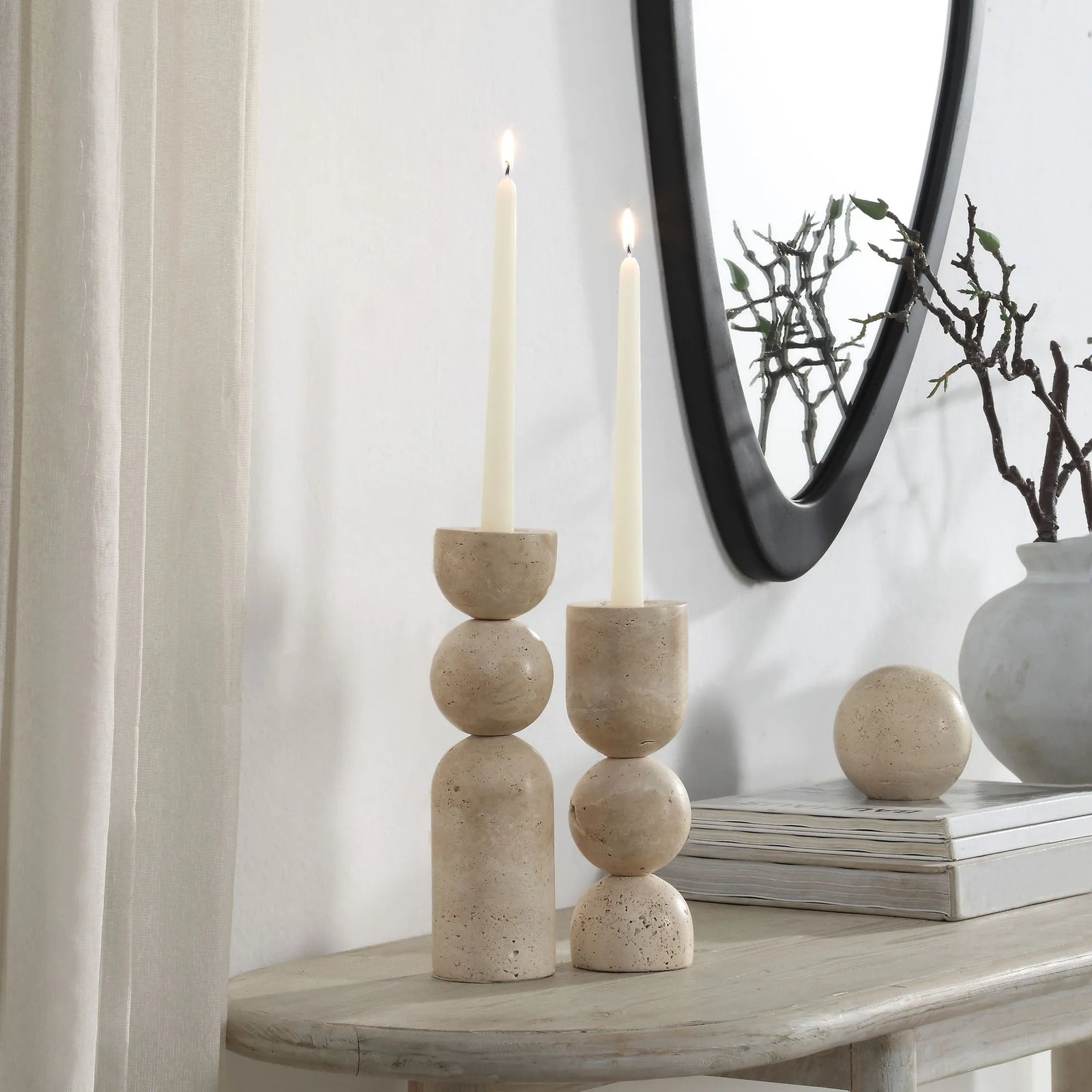 Decorative candle holders on a table with a mirror and vase in the background