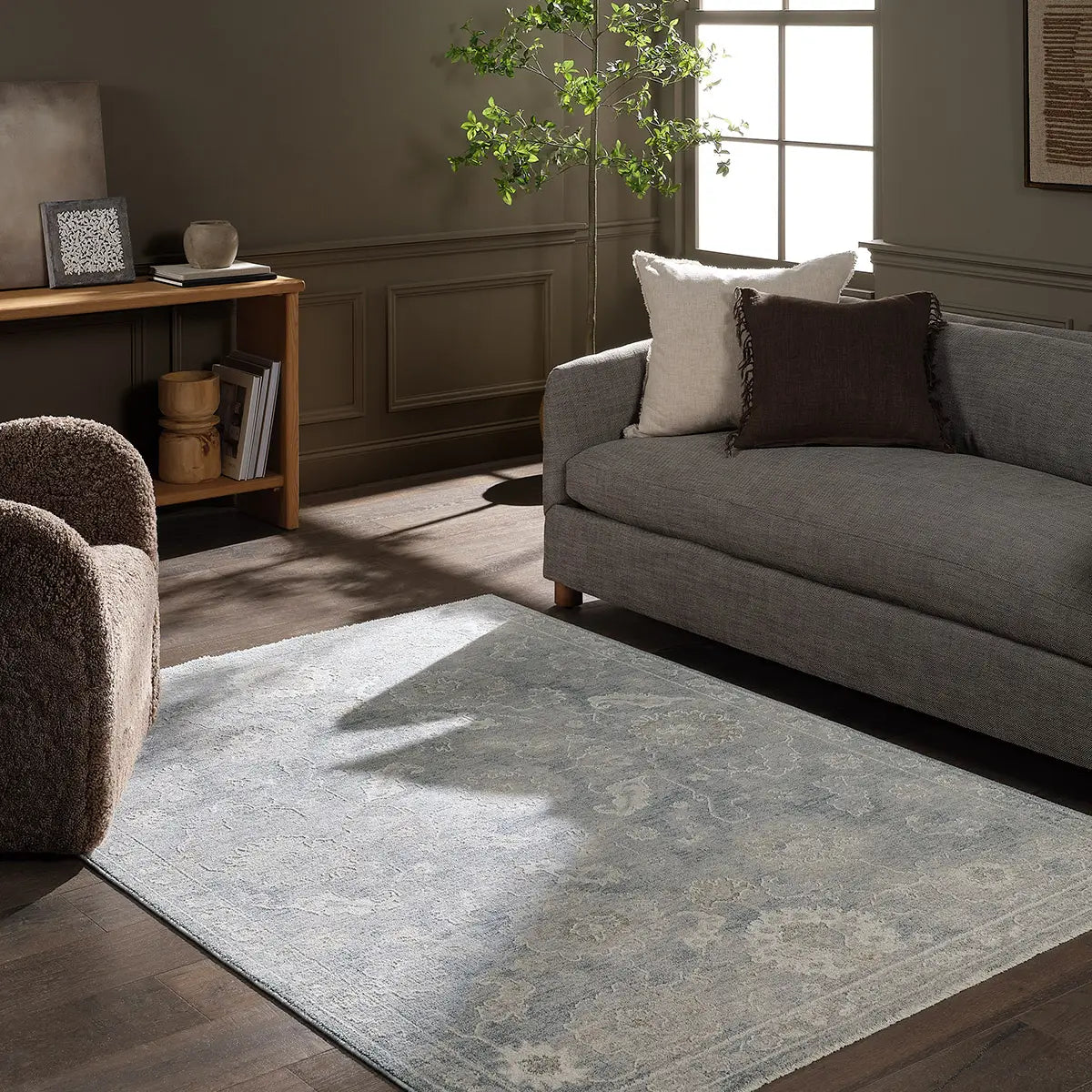 Living room with a gray sofa, armchair, and patterned rug.