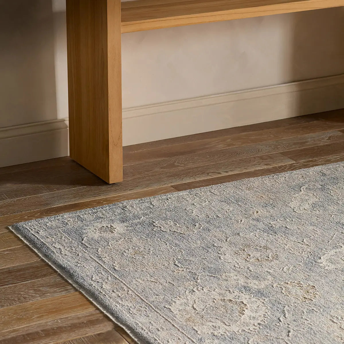Close-up of a wooden floor transition strip between a rug and a hard surface.