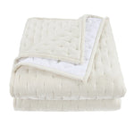 Folded beige quilt with white interior on a white background