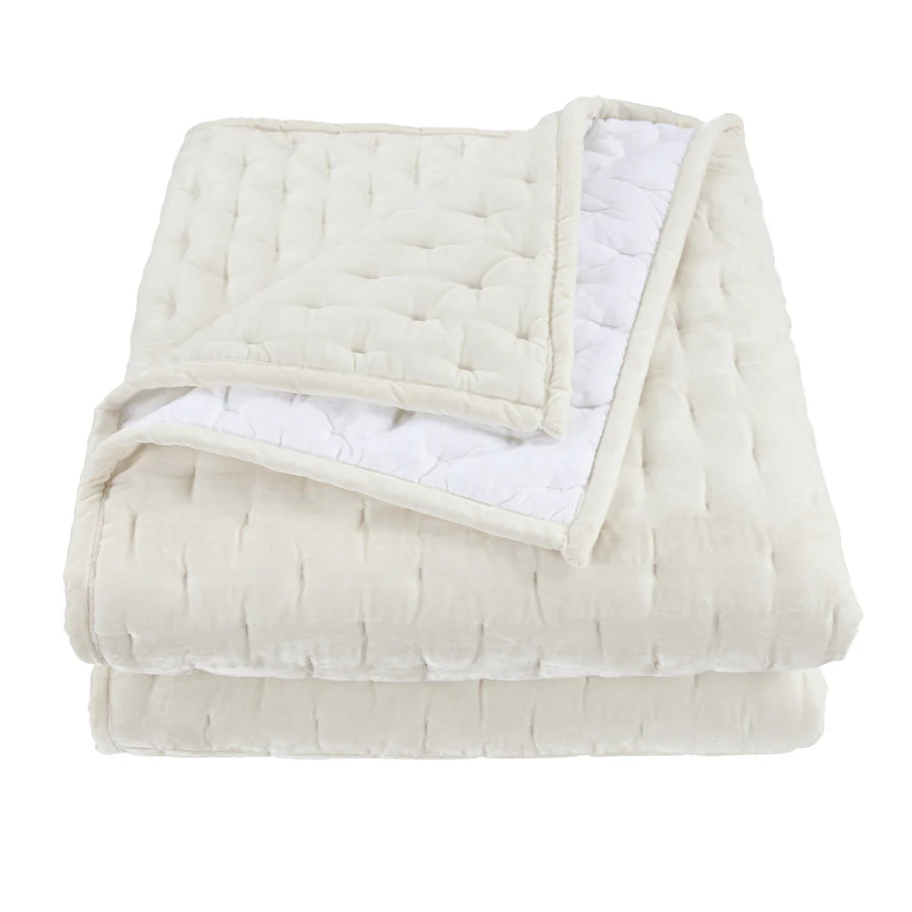 Folded beige quilt with white interior on a white background