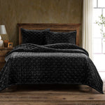 Dark quilted bedding set on a wooden bed in a bedroom setting.