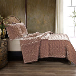 Quilted bedspread with matching pillows on a bed in a bedroom setting.