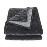 Folded dark gray quilt on a white background