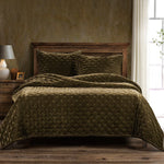 Green quilted bedding set on a wooden bed with a wooden headboard in a room with a window.