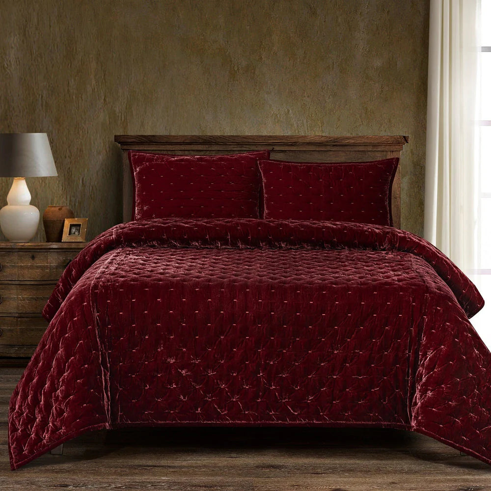 Red quilted bedding set on a bed with a wooden headboard and nightstand.